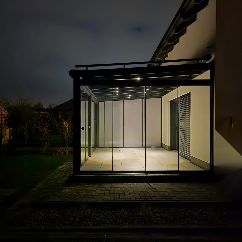 Kalter Wintergarten mit Glasschiebewänden und LED-Spots am Einfamilienhaus in Leipzig bei Nacht