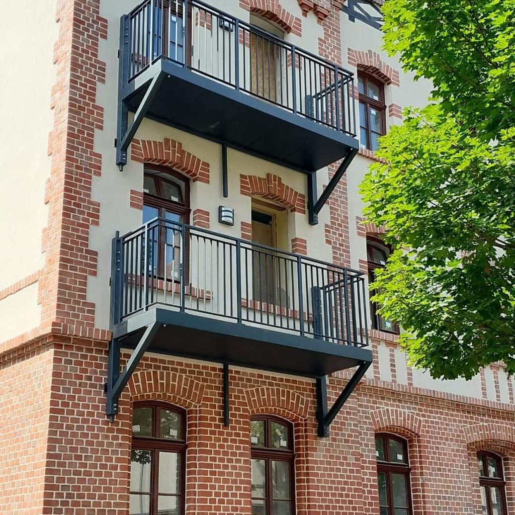 Zwei übereinander montierte Anbaubalkone aus Stahl in Anthrazit an einem Klinker-Mehrfamilienhaus im Raum Halle–Leipzig