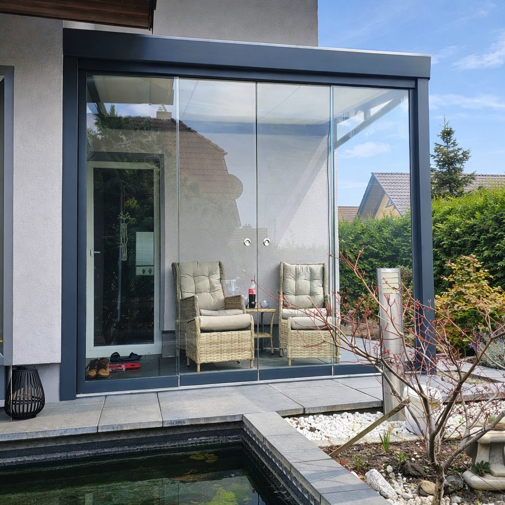 Modernes Terrassendach in Anthrazit mit Glas-Schiebewänden, Sitzgruppe und Sonnenschein am Einfamilienhaus in der Region Leipzig.